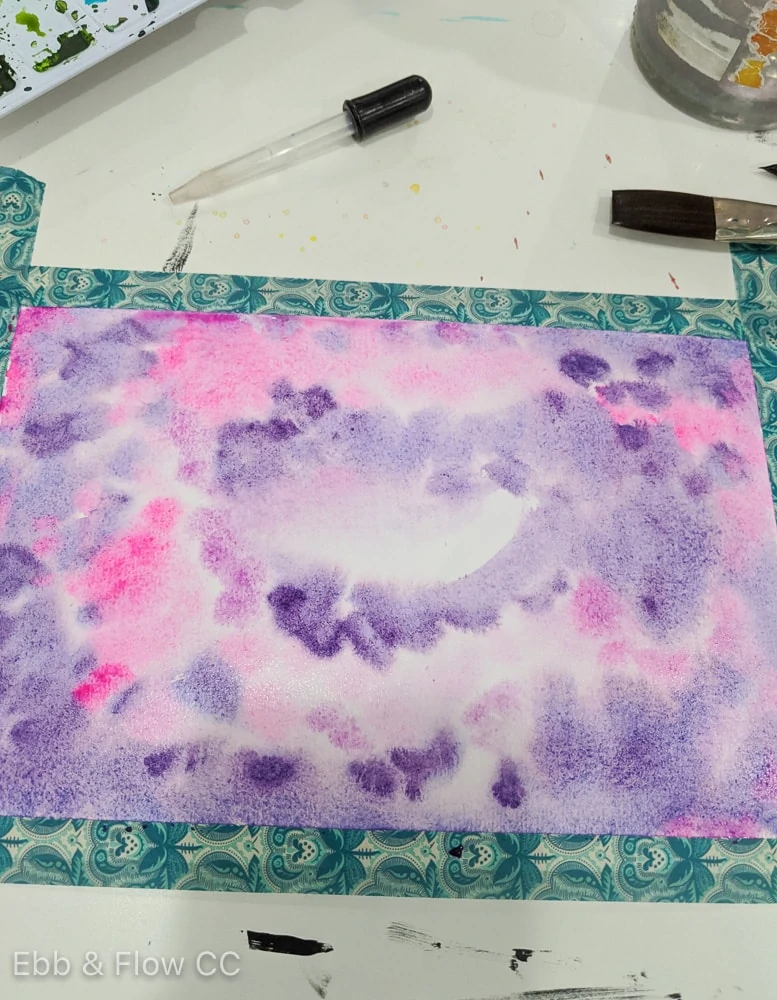 paper covered in watercolor paints in purples and pinks