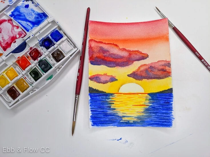 watercolor sunset over water painting with watercolor paint and brushes