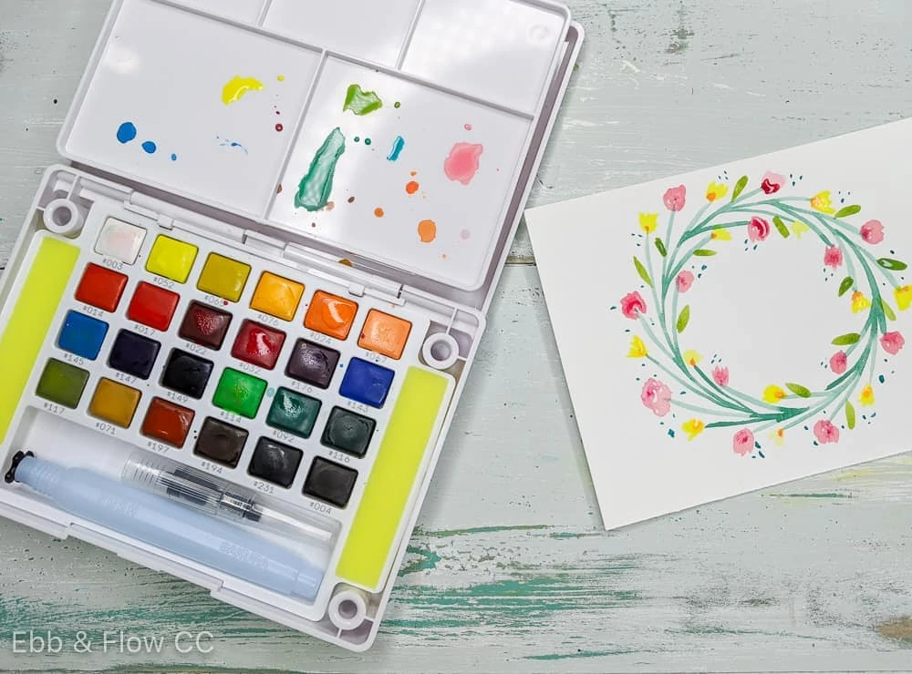 watercolor paint kit and simple floral wreath painting