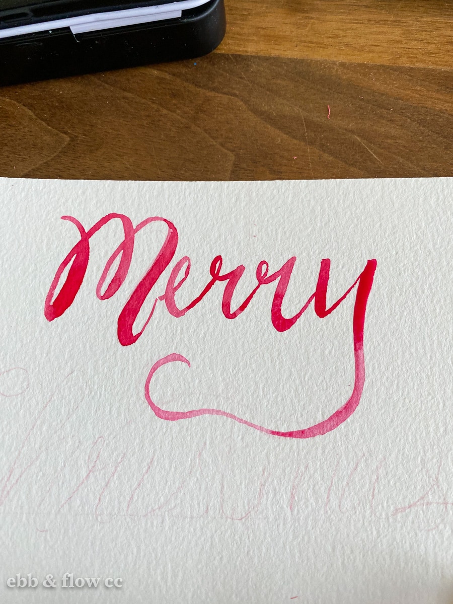 "Merry" painted in red watercolor