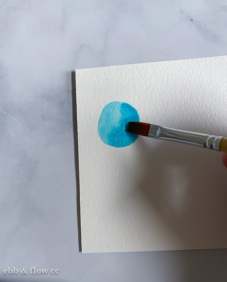 painting a teal circle shape with watercolors