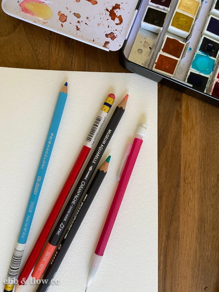 assortment of pencils by watercolor paint set