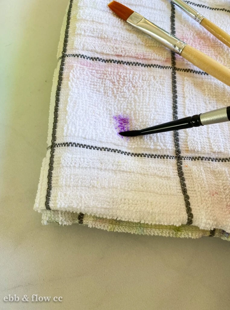 brush wiping paint on towel